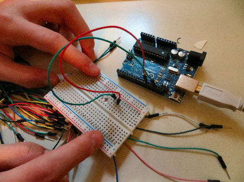 Hands working on an arduino board.