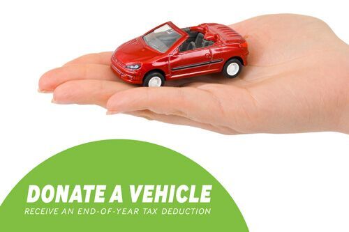 a hand holds a miniature red car with the words "donate a vehicle, receive an end-of-year tax deduction" underneath