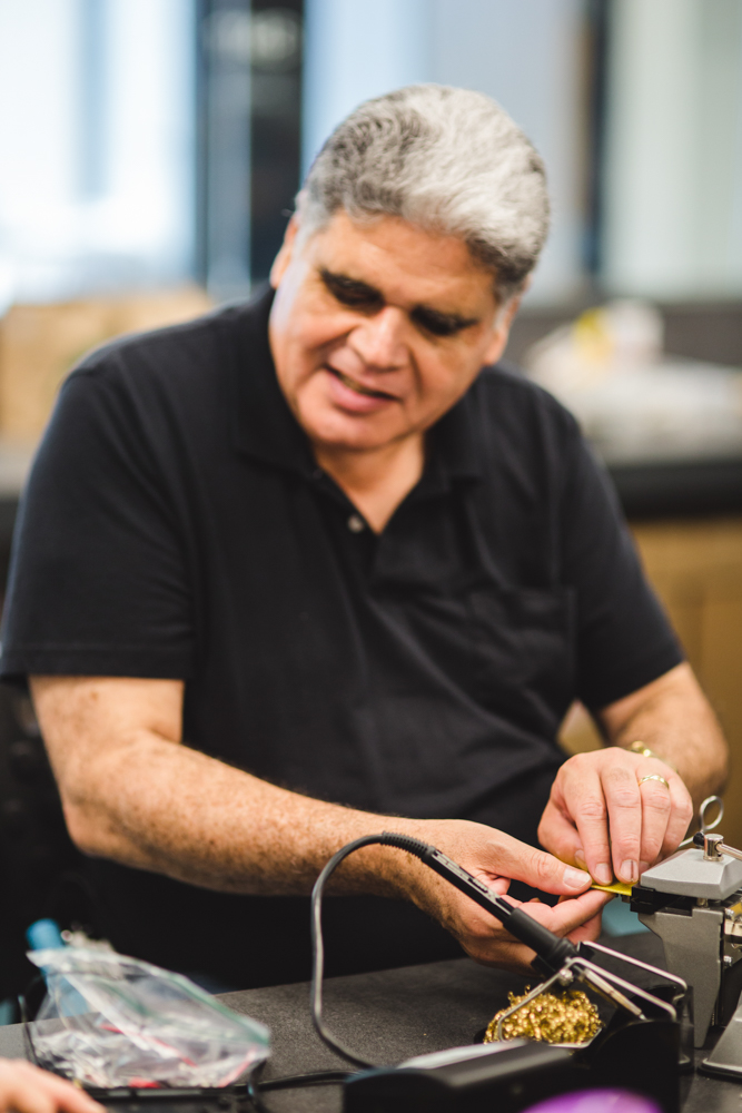 A grey-haired student in a black polo shirt glides his hands over the notches on his circuit board. 