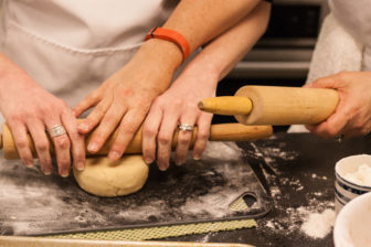 Sydney Ferrario shows student, Jane Fowler, how to use a rolling pin on dough.