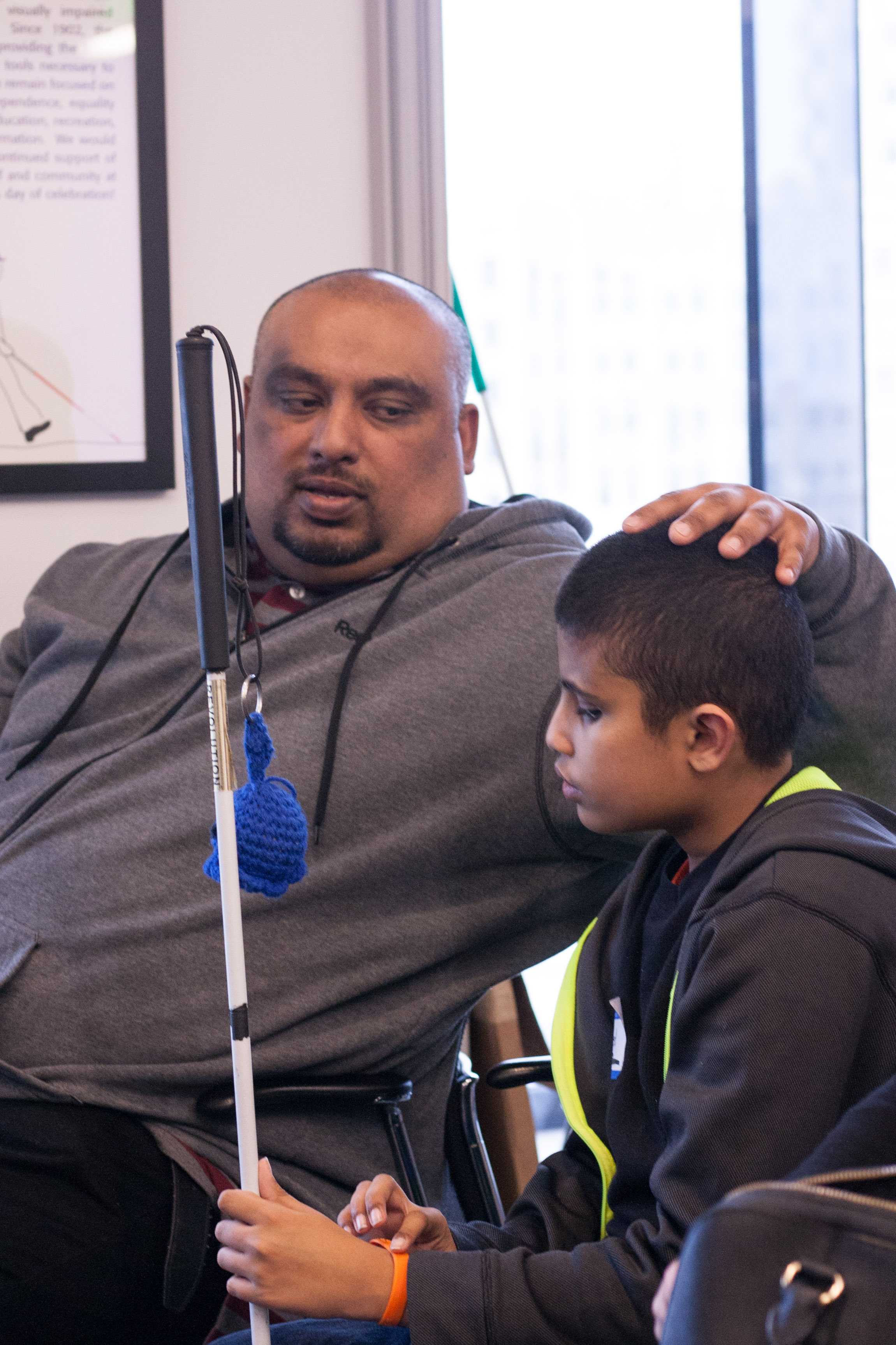 Competitor Rasheed sits next to his dad, who rests a loving hand on his head while speaking to him.