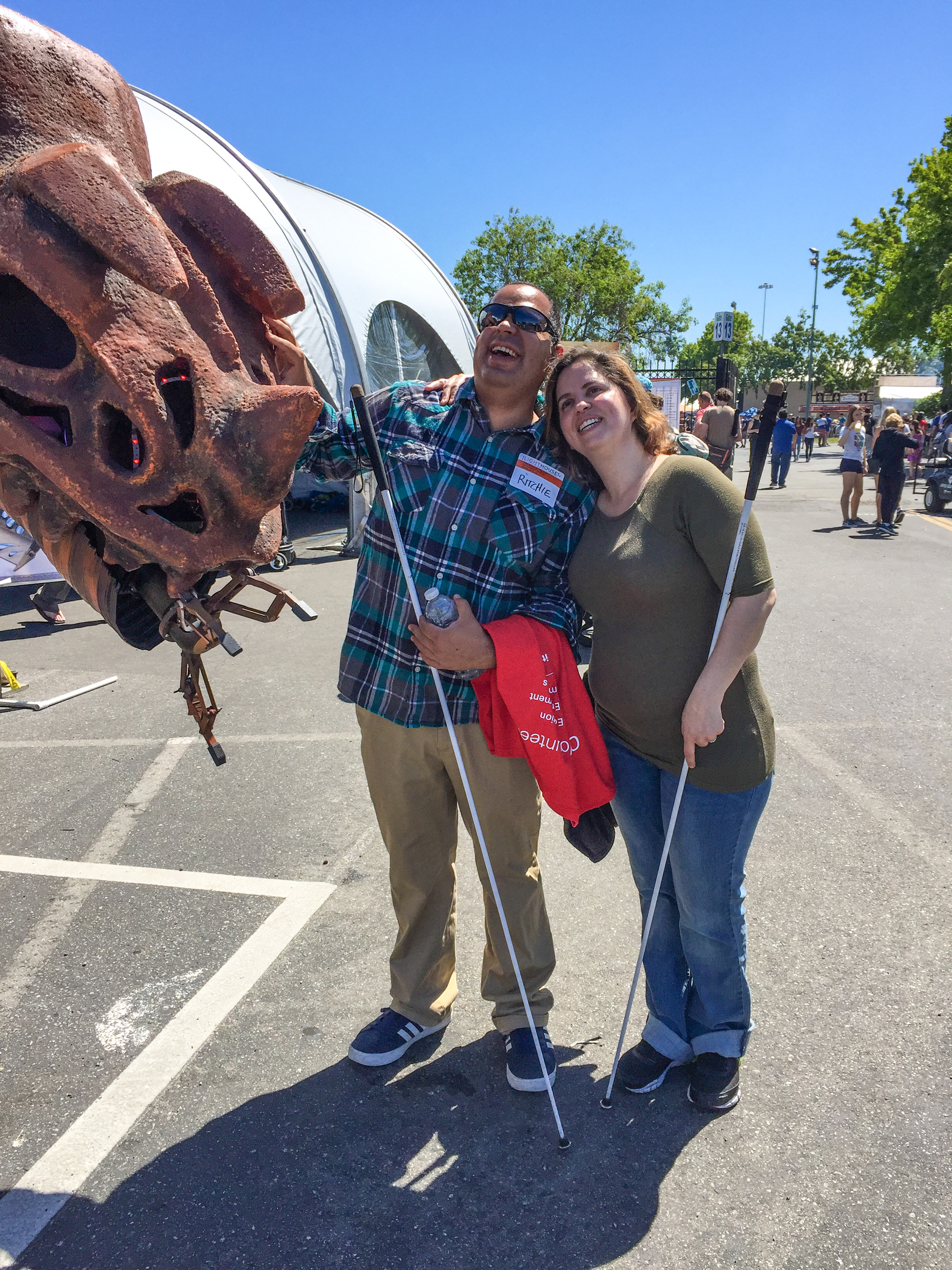 Richie and a participant stand next to a robotic dinosaur.