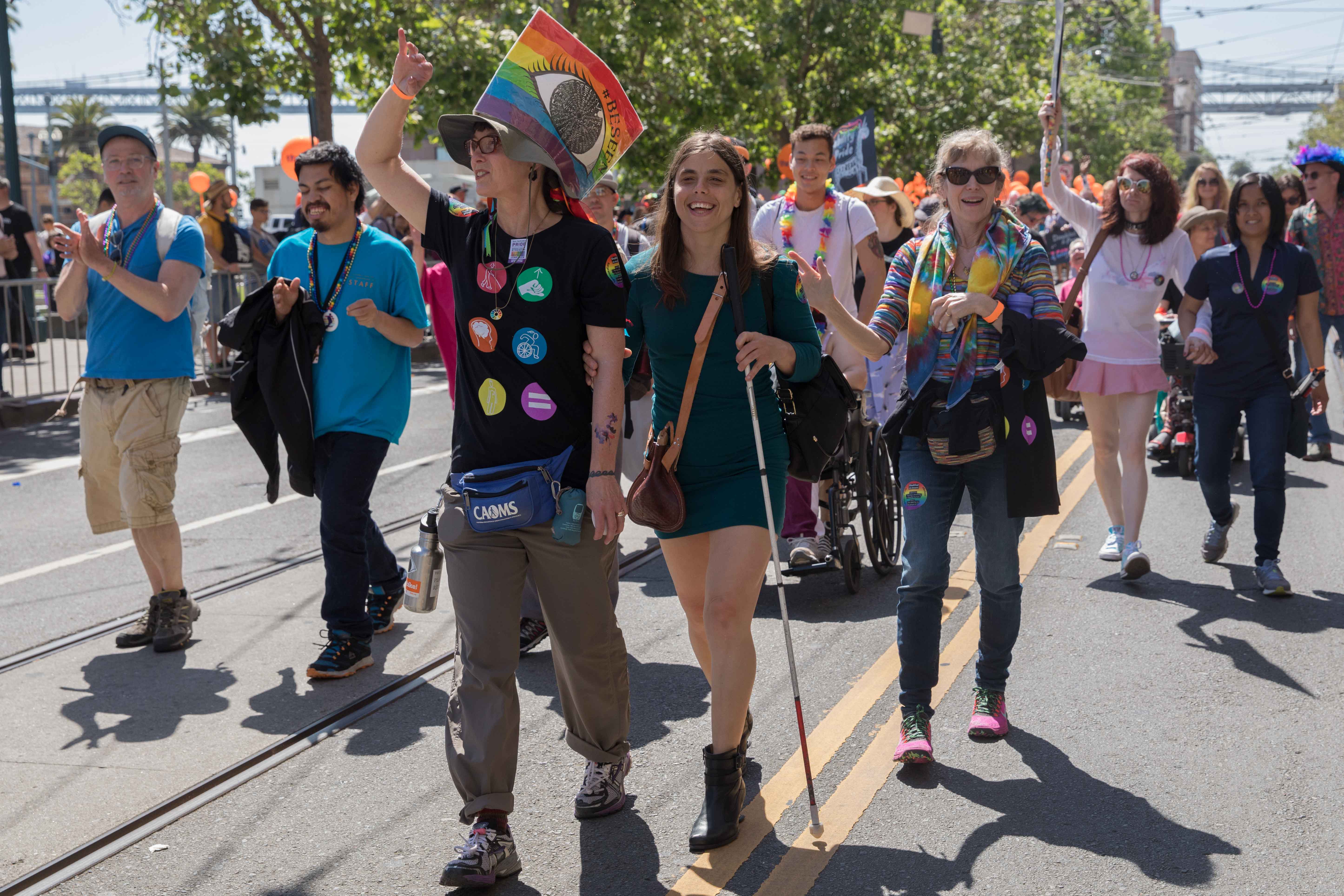 A pride participant with a cane walk side by side in the midst of our large Pride contingent.