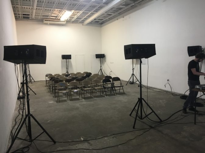 The WATS producers place speakers around a room before their immersive sounds performance.
