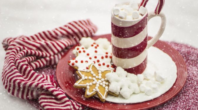 Holiday cookies and a candy cane striped mug with marshmallows and a candy cane inside.