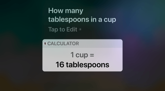 A screen capture of an iPad. Siri is asked “How many tablespoons in a cup”. The answer reads, “1 cup = 16 tablespoons”.
