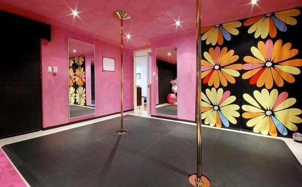 A set of poles stand in an illuminated room surrounded by mirrors and colorful, floral walls.