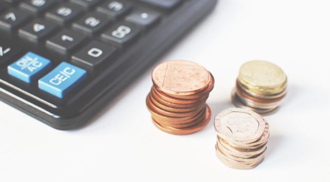 A corner of a calculator along stacks of pennies