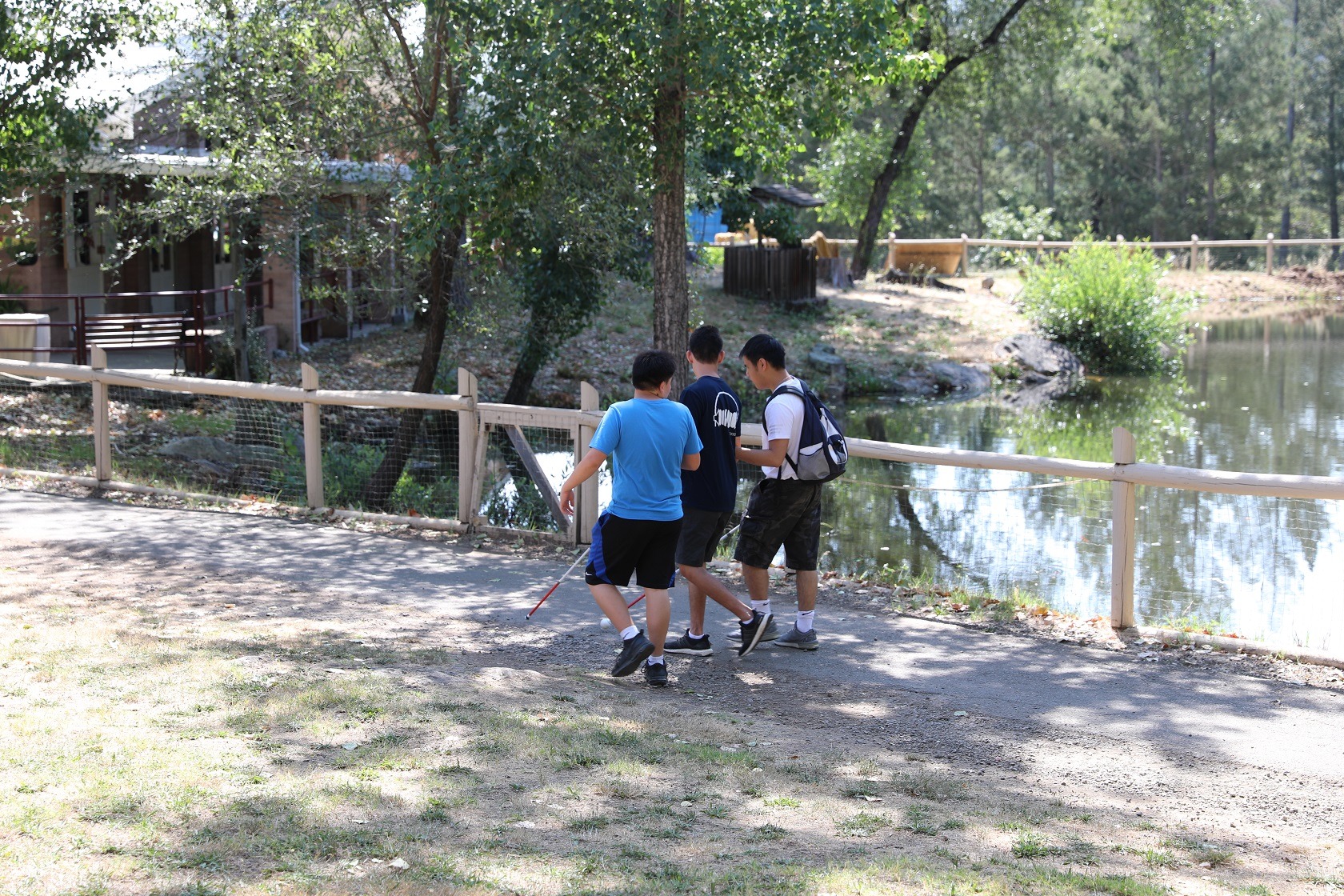 Campers with white canes walk in front of peaceful Lake Lokoya. 