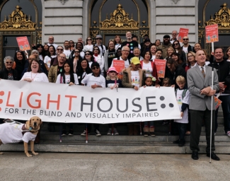 LightHouse staff, students, and supports stand outside San Francisco City Hall holding a LightHouse banner