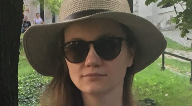 A headshot of Anna Wroblewska outdoors wearing sunglasses and a straw hat.