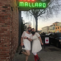 Two people wearing white dresses, masks and running shoes pose for a photo