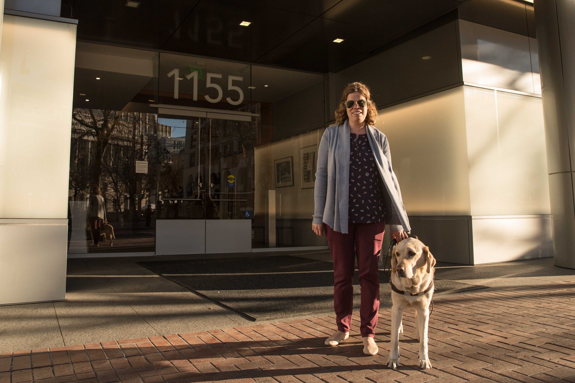 Access Technology director Erin Lauridsen standing outside LightHouse headquarters with her guide dog Kendall