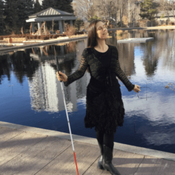 Dr. M. Leona Godin stands on a dock holding her white cane
