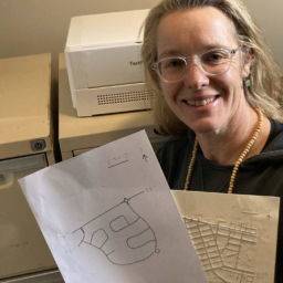 Orientation and Mobility specialist, Anegla Reynolds, poses with two TMAPs she has embossed for clients in Australia