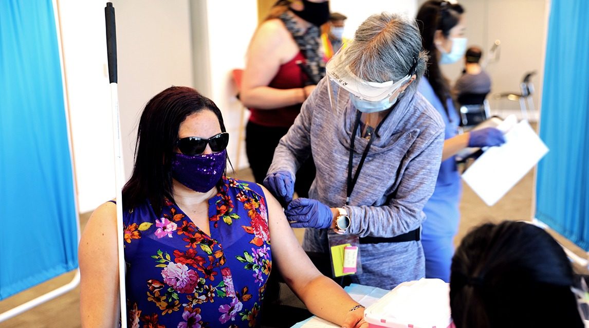 A nurse preps a person to receive a COVID-19 shot at LightHouse in 2021