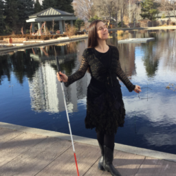 Dr. M. Leona Godin stands on a dock holding her white cane