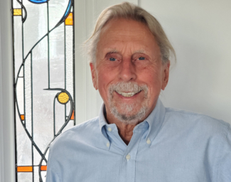 Jerry Kuns stands beside a stained glass window