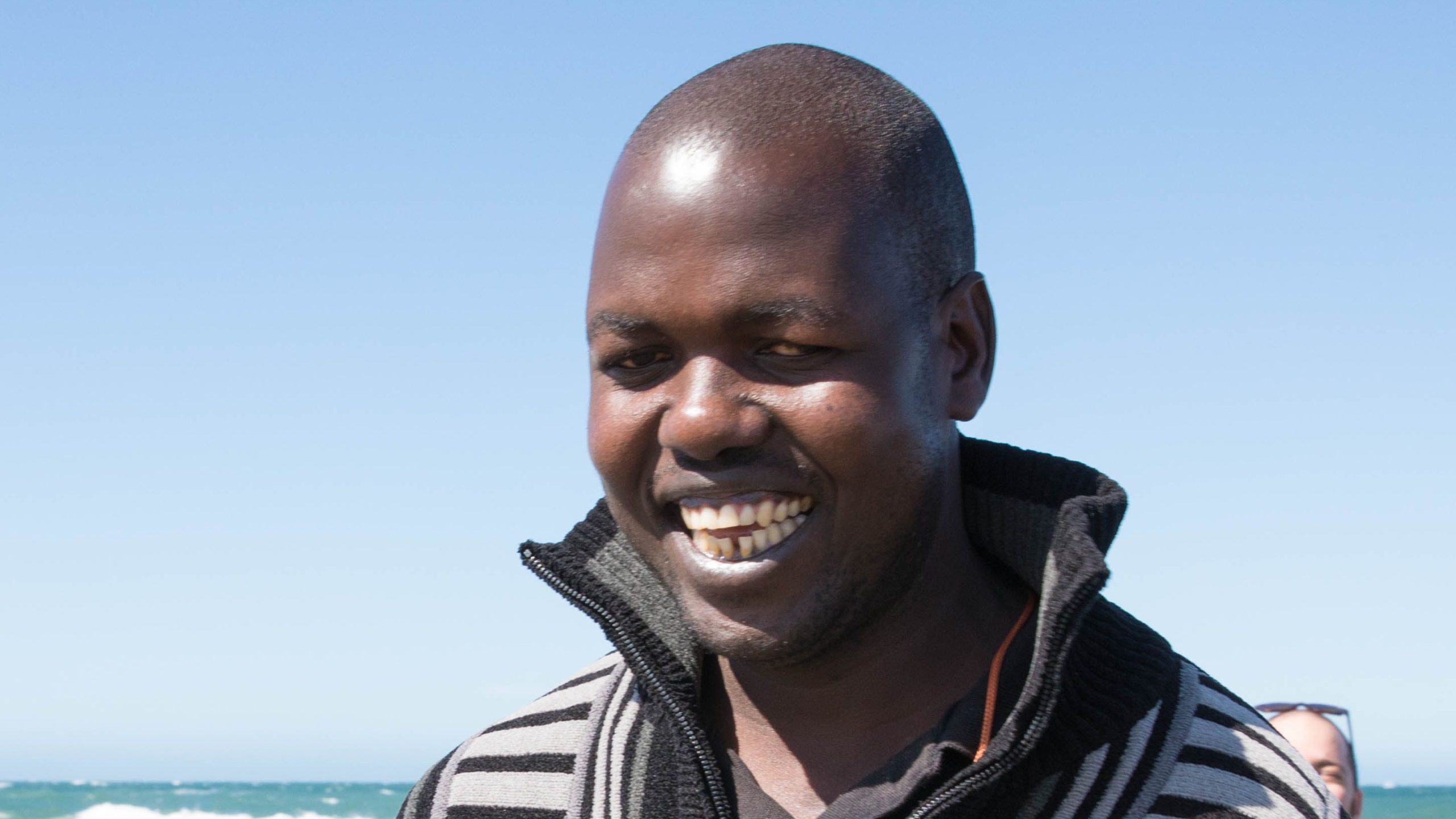 Ojok Simon smiles at the beach