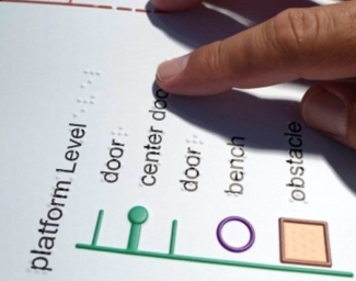 A closeup shot of a tactile BART Station map and a person reading the Braille labels with their fingers
