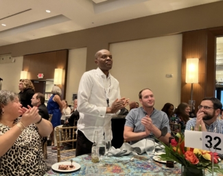 Dr. Charles Umo stands at a table at the 2022 NIB Conference