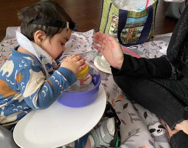 Little Learners stacks toy objects in a bowl while Maisara watches