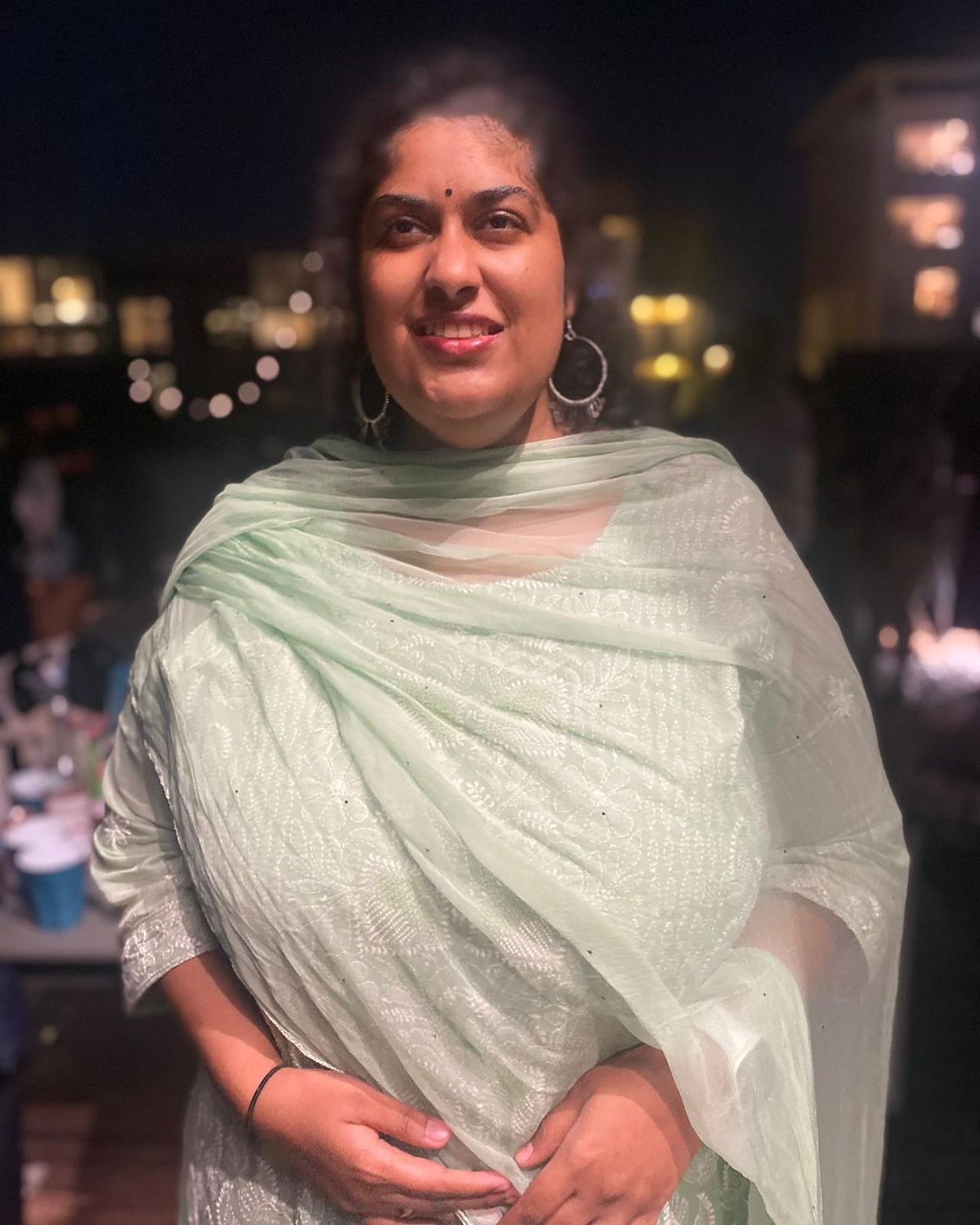 Anusha wearing hoop earrings and a pale green gown