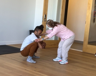 Gravity dancer, Gabrielle, Christian squats, and hold the hands of student Katlau, who bends over face-to-face and close up as they work together during and improvisational movement class.at LightHouse