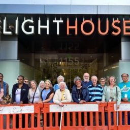 The June 2023 CVCL students and staff stand outside LightHouse headquarters. They are lined up behind an orange barricade
