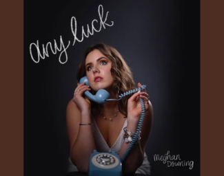 Meghan Downing’s cover art for her single “Any Luck”. She is looking up and off to the right side while holding the handle of a blue rotary phone.