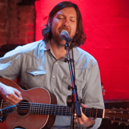 Graham Norwood singing while playing guitar