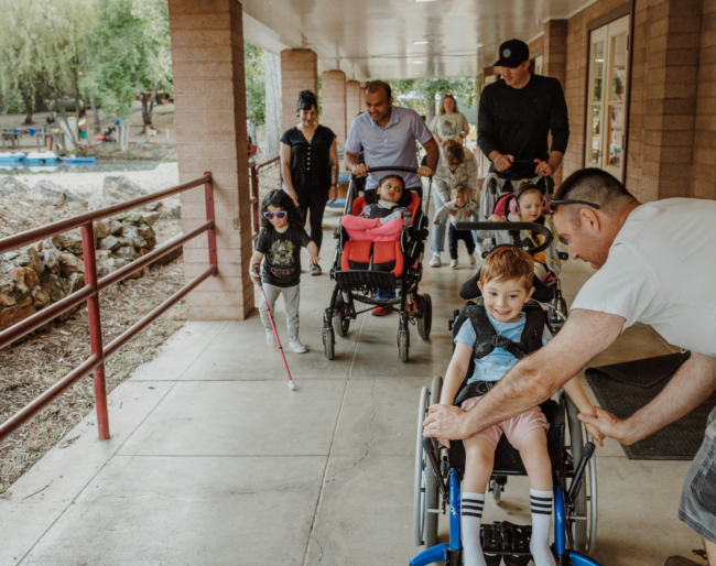 A group of families walking past the Dining Hall at Little Learners Family Camp