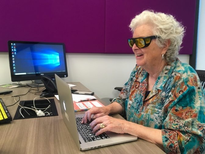 A student wearing yellow fitover sunglasses types at a laptop in a LightHouse tech lab