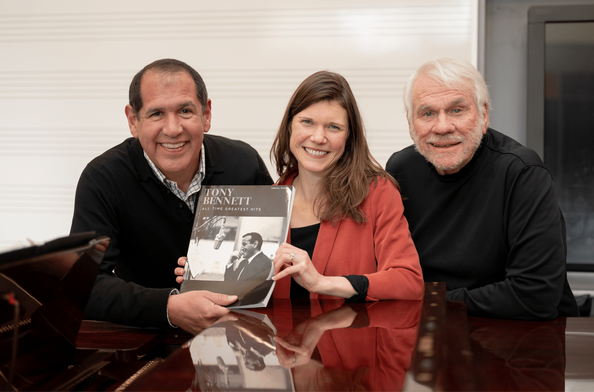 Alex Perez, Marie Finch and Steve Gill pose together holing a book about Tony Bennett