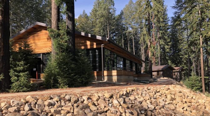 A new structure at EHC with external wood paneling, large windows, and is surrounded by redwood trees and newly paved paths