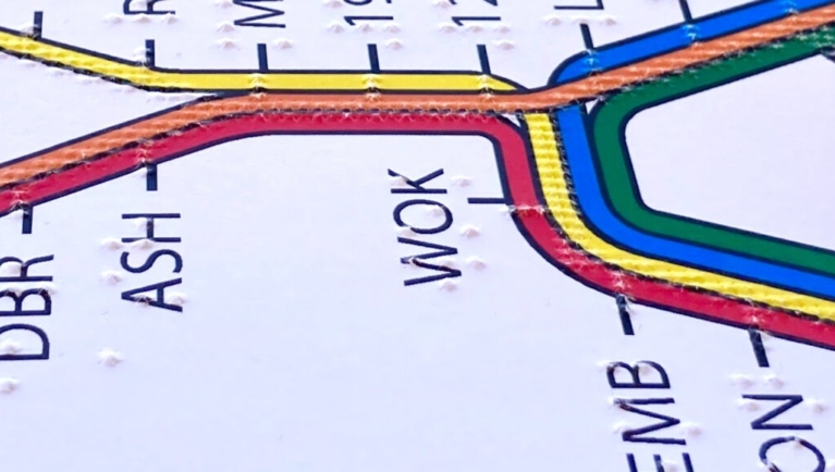 A finger explores a tactile BART system map.