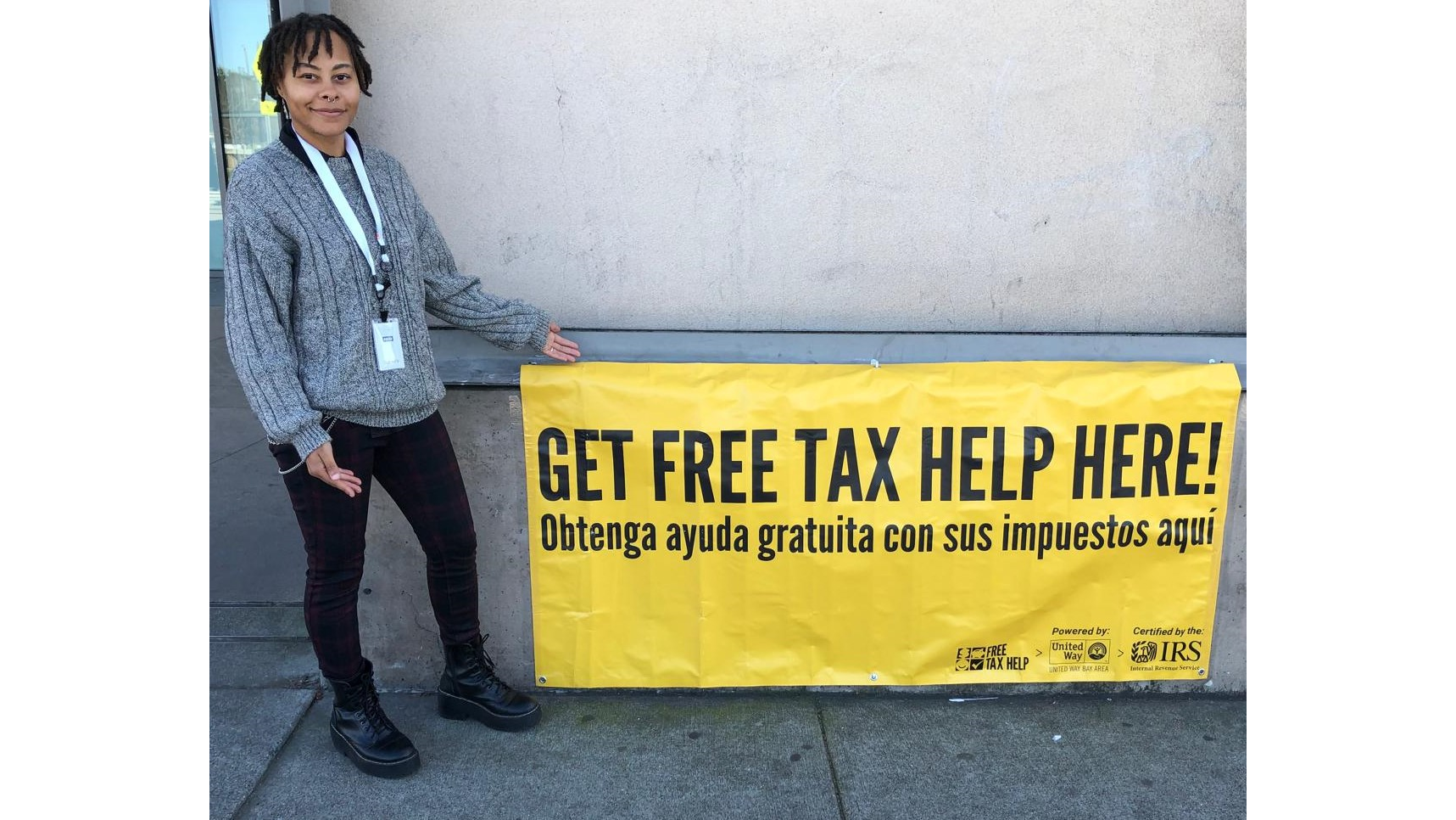 A person holding a sign that reads get your free tax help here!