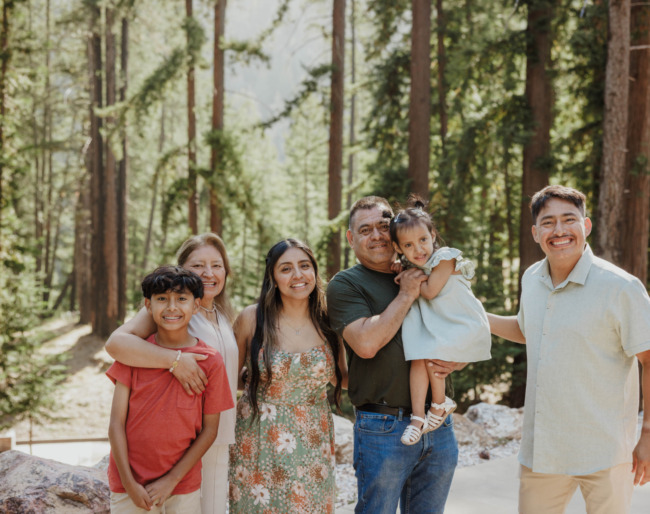 A family of six pose together on a trail at EHC surrounded by redwood trees. Photo credit: Emmalaine Berry Photography