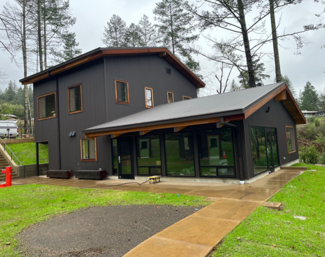 A large, two-story structure with lots of large windows and a freshly paved path leading up to it