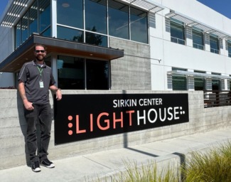 Taylor stands beside the LightHouse Sirkin Center sign at our manufacturing facility in Alameda