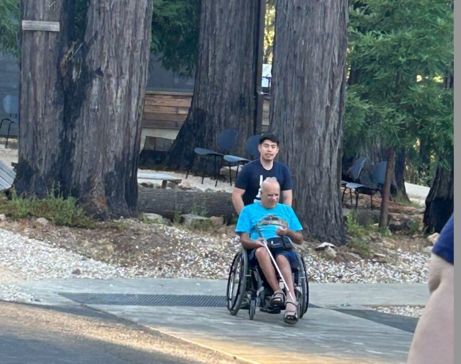 Ken Rossi sits in his wheelchair and is being pushed by a counselor at EHC
