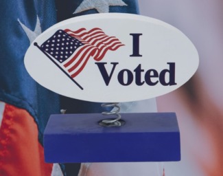 A blue ballot box with a sign that says I Voted" and an American flag next to it