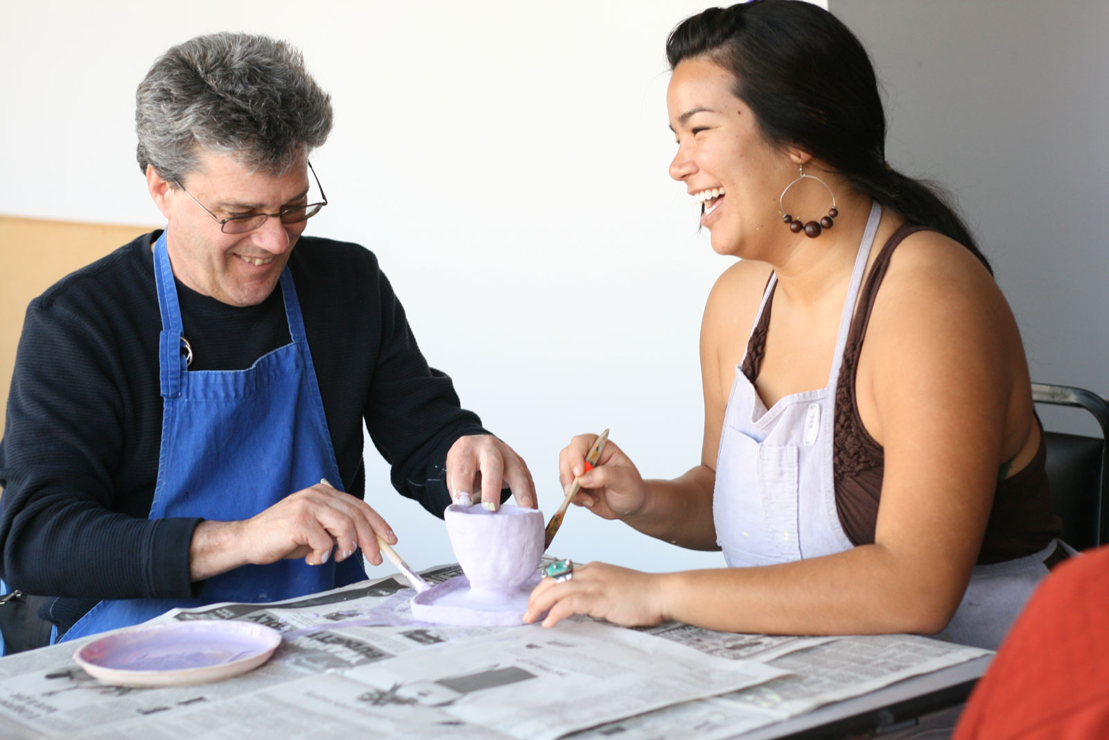 Two LightHouse studios smile as they work on a pottery project