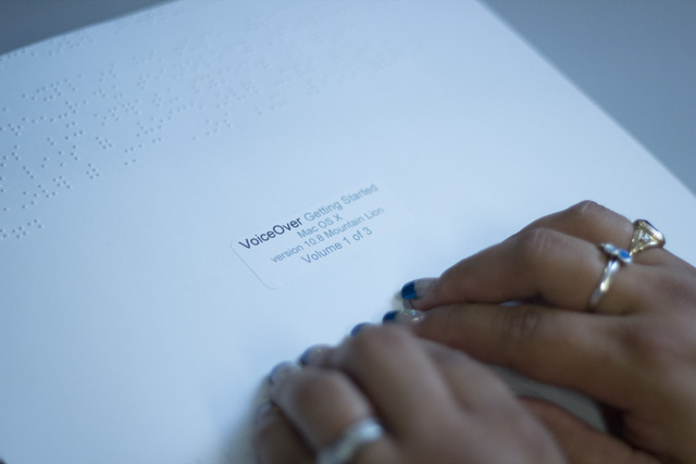 Fingers read Braille version of the Voiceover Guide for Apple’s Mountain Lion Operating System