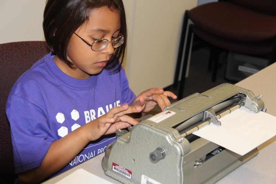 A young Braille Challenge participant loads her brailler with paper.