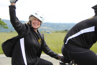 At Cycle for Sight 2014, Team LightHouse member Kate Williams raises her arm in greeting as she and her captain enjoy the speed of a tandem