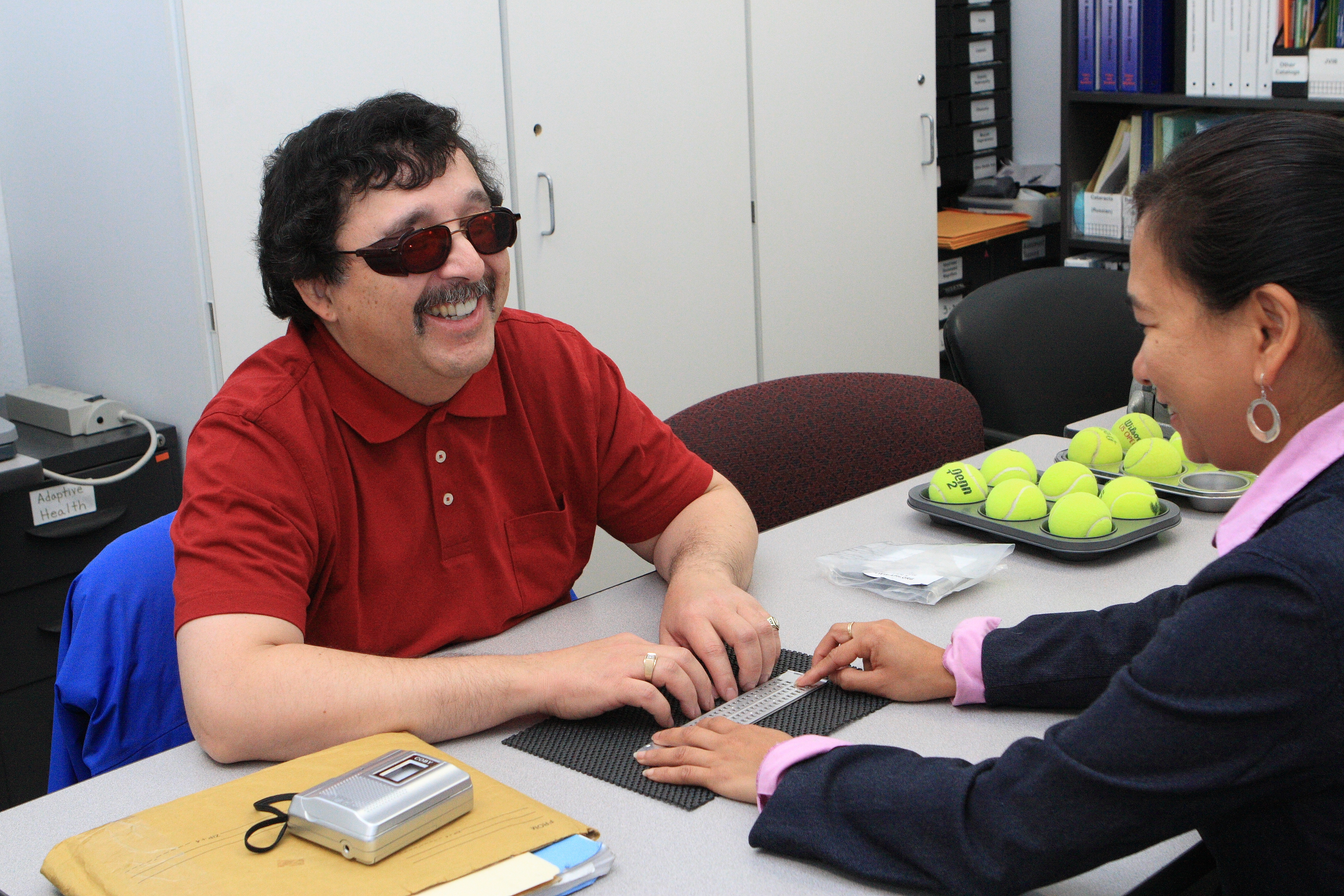 LightHouse braille instructor Divina Carlson teaches braille to a smiling student