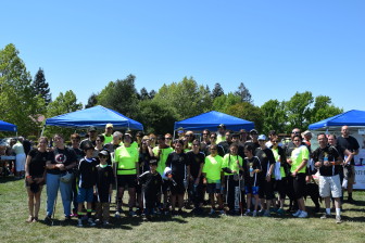 A large group of Team LightHouse members gather in front of the LightHouse table at the festival