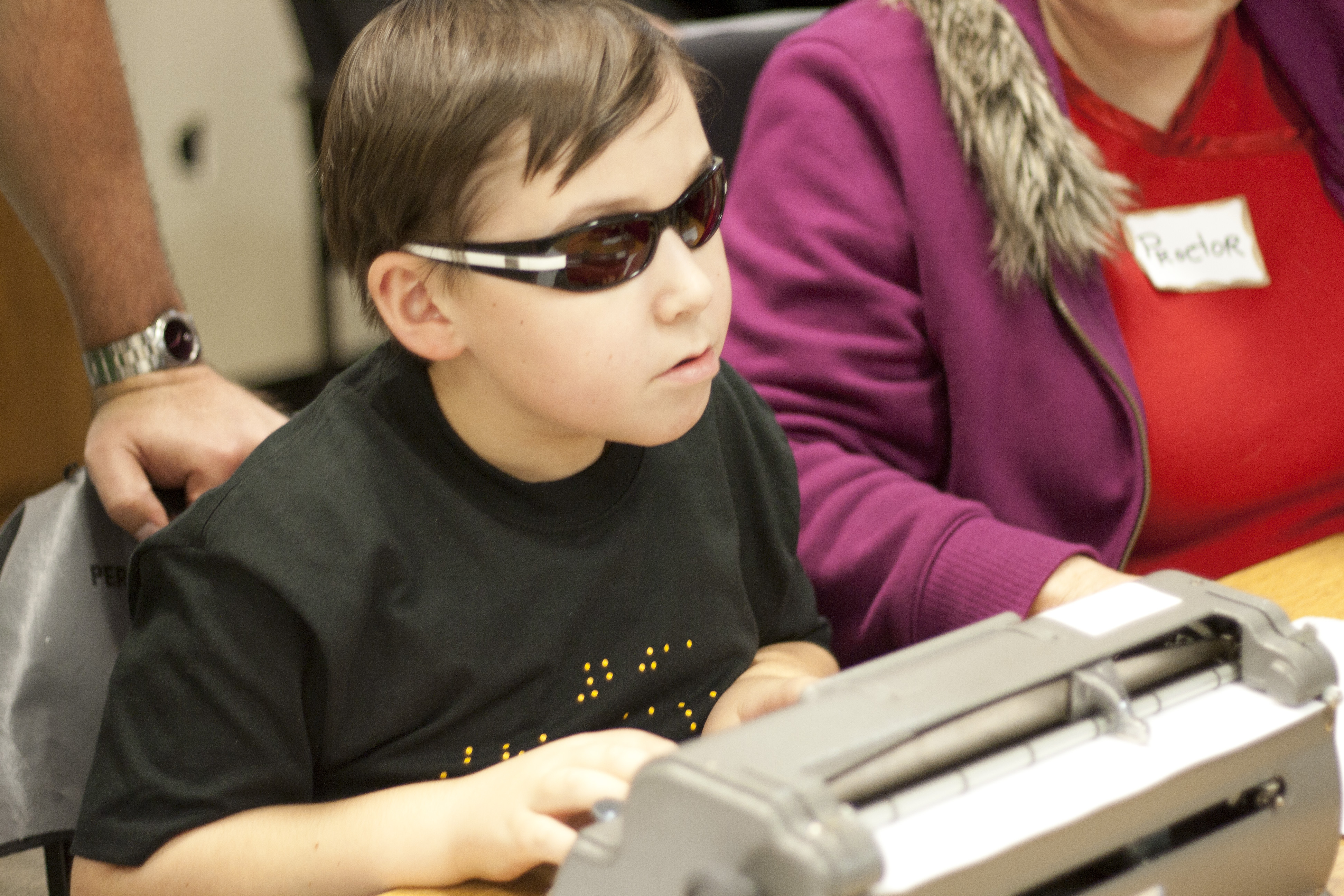 Young boy types diligently on a Perkins Brailler during the Braille Challenge
