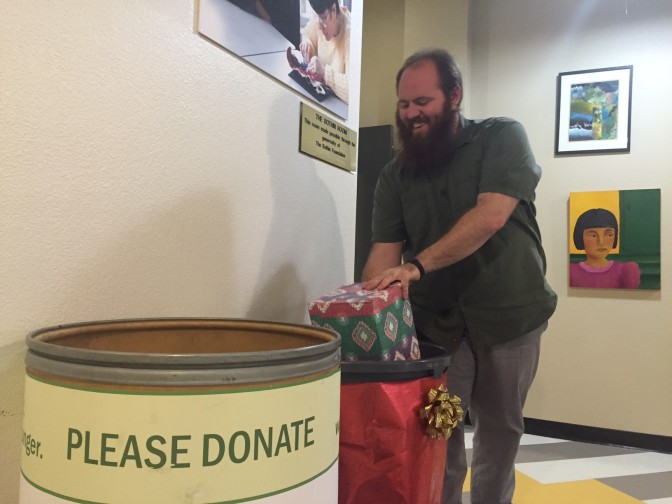 LightHouse Youth Services Coordinator Jamey Gump places a donation in the LightHouse Holiday Drive barrel